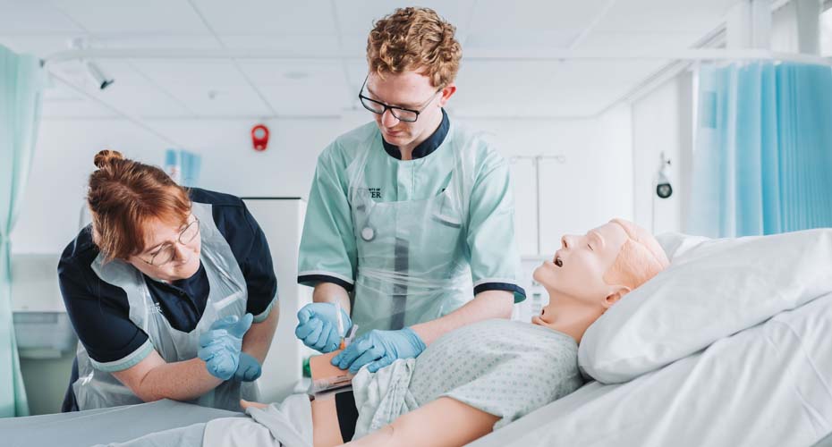 Student nurses practising injections on manekin