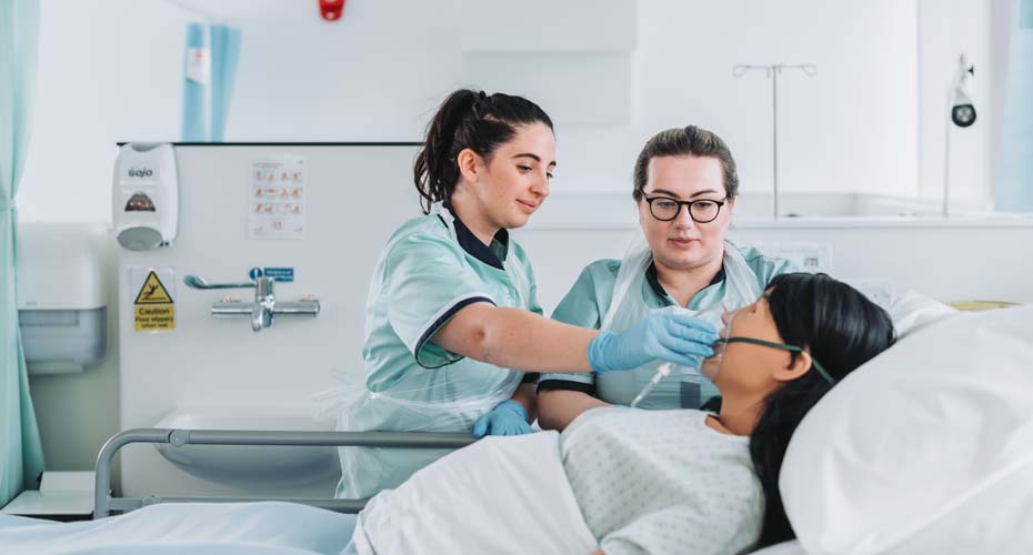 Nursing students using oxygen mask on manekin