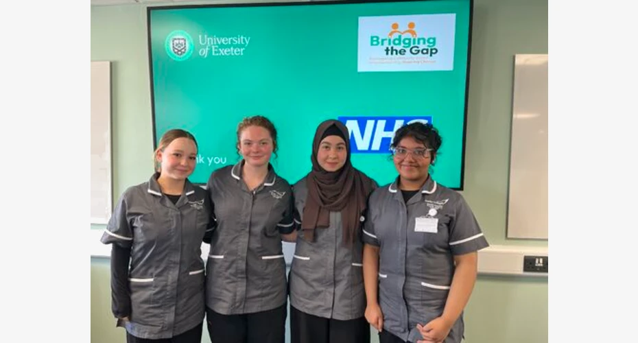 Picture of 4 T Level students stood Infront of a large tv screen.